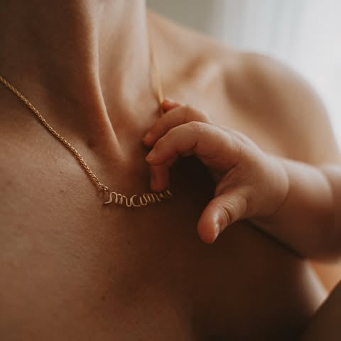 baby's hand touching maman writing necklace in gold Atelier Paulin push present