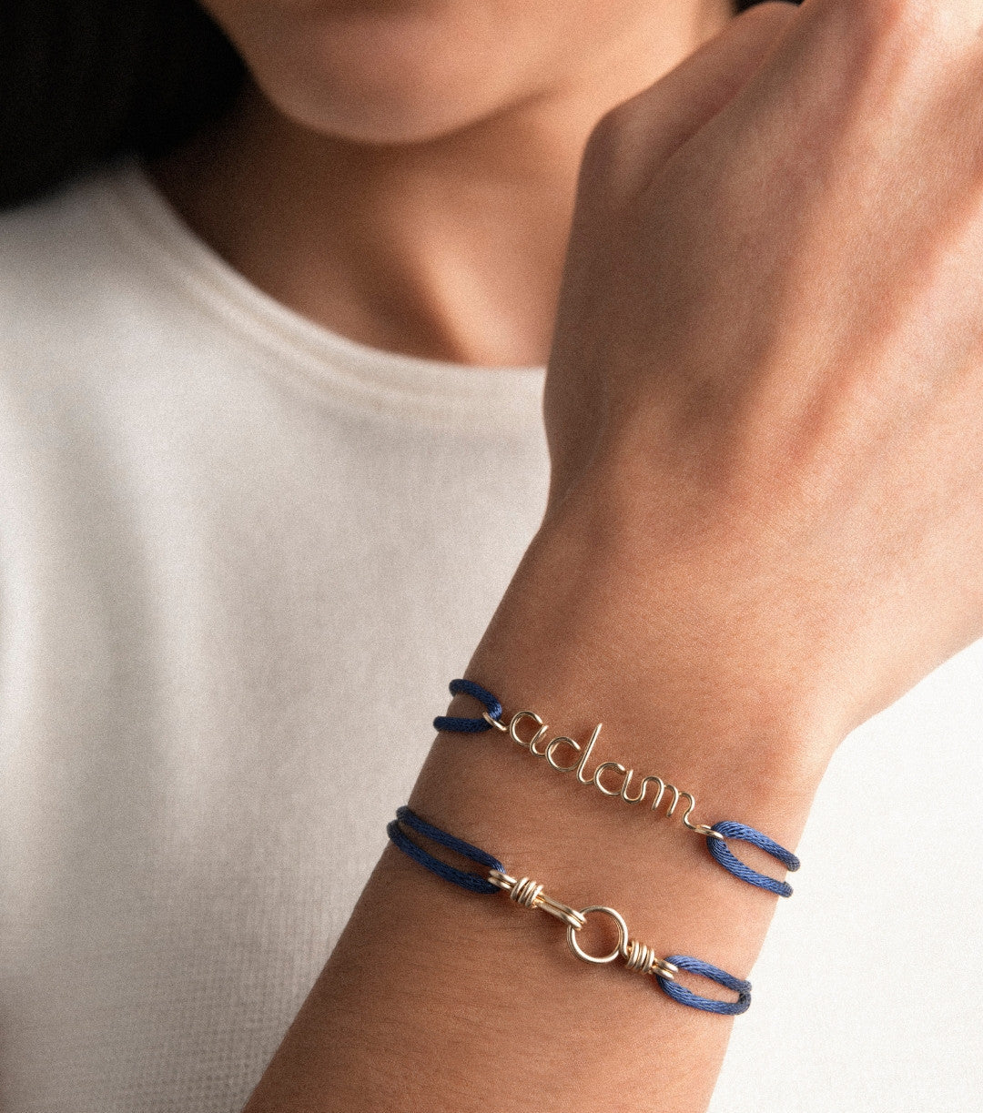 Blue cord bracelet on wrist with personalised name in silver wire, handcrafted by Atelier Paulin